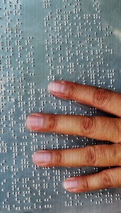 metal braille with hand reading